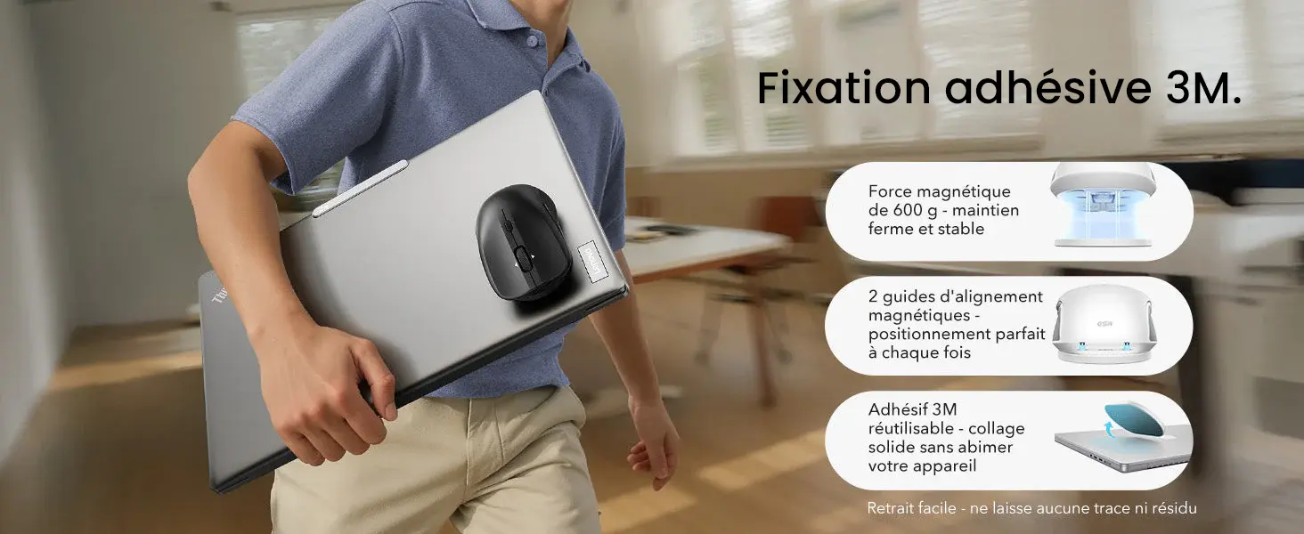 Infographie explicative de la fixation adhésive 3M de la souris ESR MagMouse. Visuel d'un utilisateur transportant son ordinateur portable avec la souris noire aimantée au dos. Détails techniques présentés : force magnétique de 600 g pour un maintien ferme, 2 guides d'alignement magnétiques pour un positionnement parfait, et adhésif 3M réutilisable offrant un collage solide sans résidu ni dommage pour l'appareil.