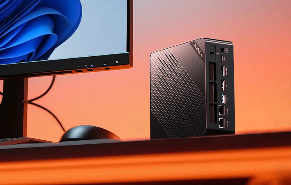 Mini PC MINIX ER937 installé à côté d'un écran avec son format compact et ses nombreuses connexions.